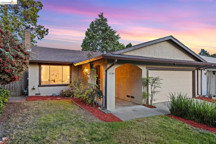 Ranch-style home featuring a garage, stucco siding, a chimney, and roof with shingles