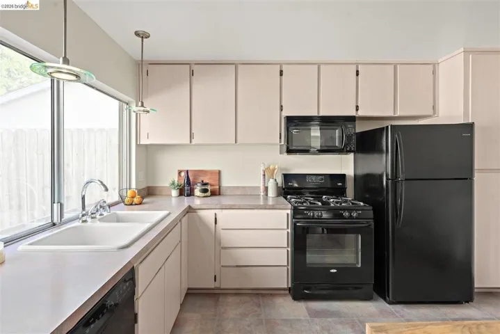 Kitchen featuring black appliances, light countertops, and cream cabinets