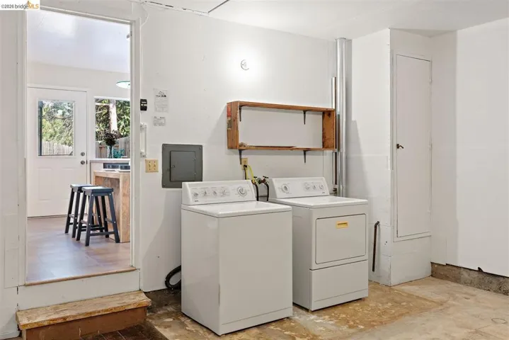 Laundry room with electric panel and washer and clothes dryer