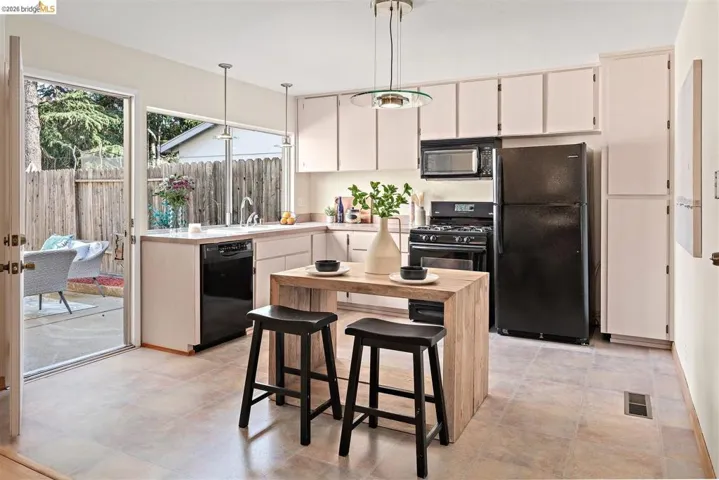 Kitchen featuring light countertops, black appliances, pendant lighting, and white cabinetry
