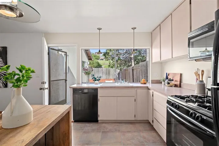 Kitchen featuring black appliances, butcher block countertops, and pendant lighting