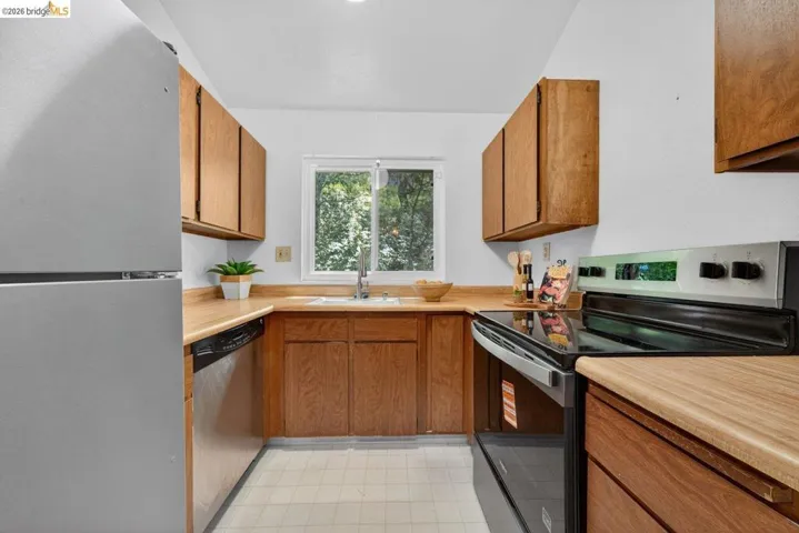 Kitchen featuring stainless steel appliances, wood finish cabinetry, light countertops, and light floors