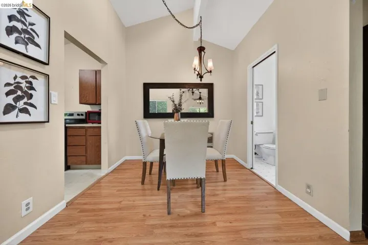 Dining room with a chandelier, light wood-style flooring, and vaulted ceiling
