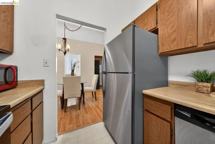 Kitchen featuring wood finish cabinets, light countertops, stainless steel appliances, and a textured wall