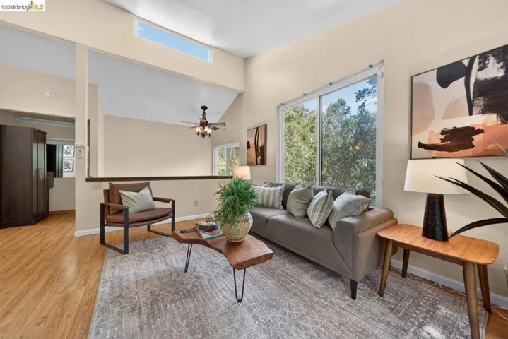 Living room with light wood finished floors, a high ceiling, and ceiling fan