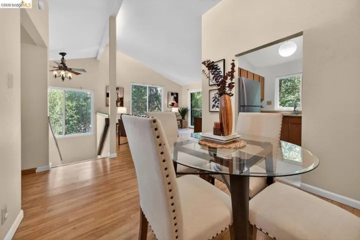 Dining area featuring light wood-style floors, vaulted ceiling, and ceiling fan