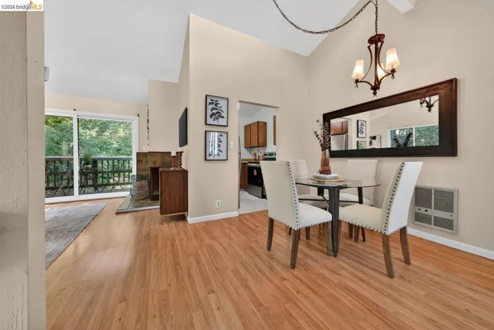 Dining space featuring heating unit, light wood-style floors, lofted ceiling, and suspended lighting