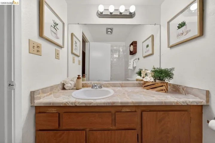 Full bath featuring vanity, a shower, and a textured wall