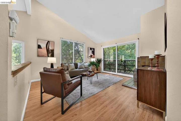 Living area featuring light wood-style floors, vaulted ceiling, and plenty of natural light