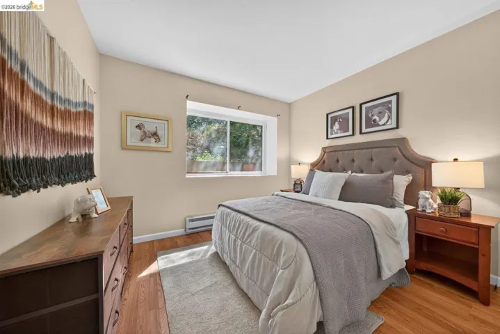 Bedroom with light wood finished floors and baseboard heating
