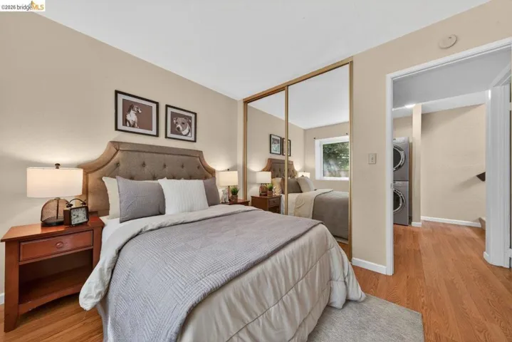 Bedroom with stacked washing machine and dryer, light wood finished floors, and a closet