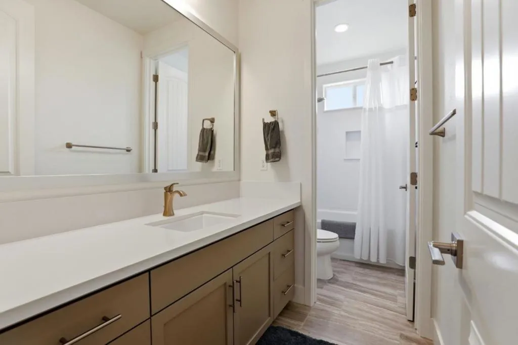 Modern bathroom featuring quartz countertops, upgraded cabinetry, and a shower/tub combo.