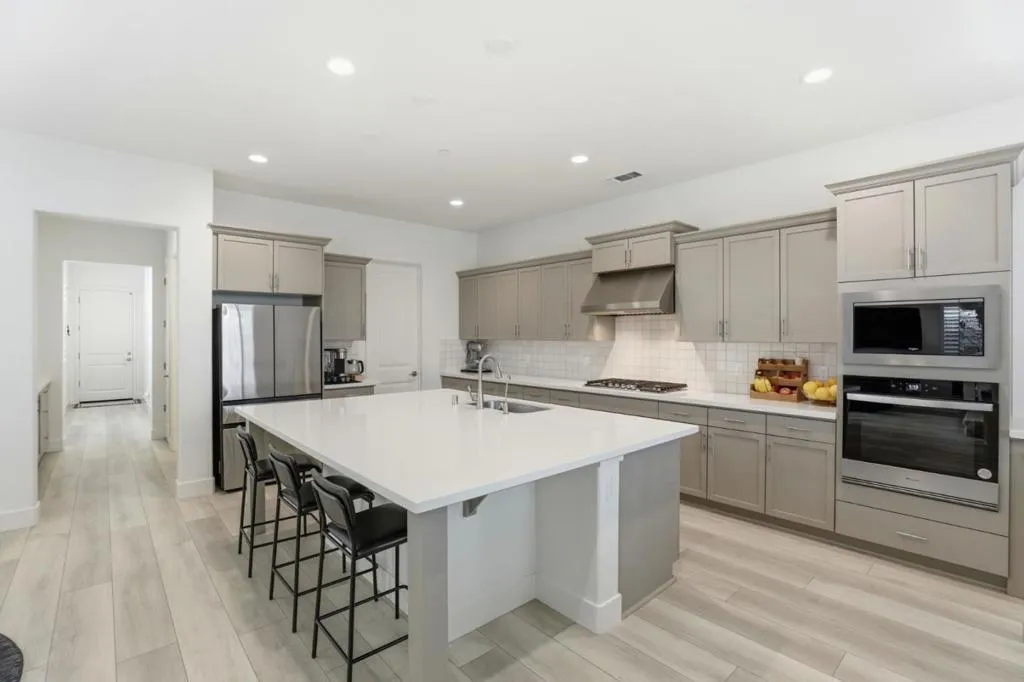 Spacious open-concept kitchen featuring a large quartz island with seating, upgraded cabinetry.