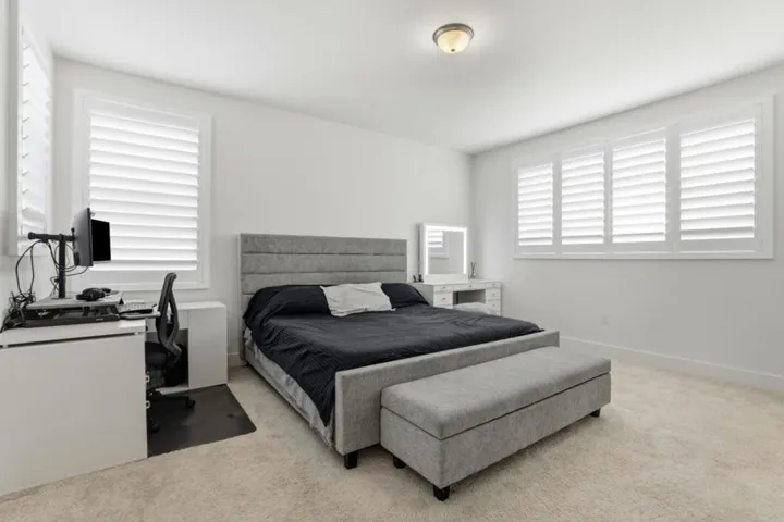 Bright and spacious bedroom featuring shutters, plush carpeting, and a versatile layout.