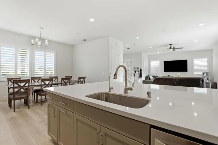 Quartz island with built-in sink anchors this open-concept kitchen.