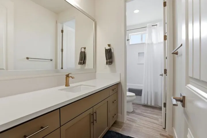 Modern bathroom featuring quartz countertops, upgraded cabinetry, and a shower/tub combo.