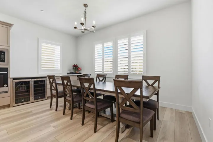 Dining area bathed in natural light, featuring shutters and a built-in wine refrigerator.