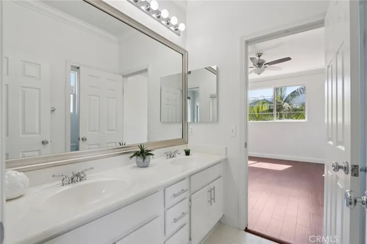 Dual-sink vanity with generous counter space and a bright layout flowing into the adjoining bedroom
