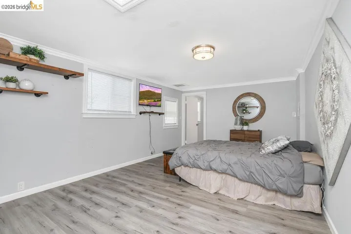 Bedroom with light wood-type flooring and crown molding