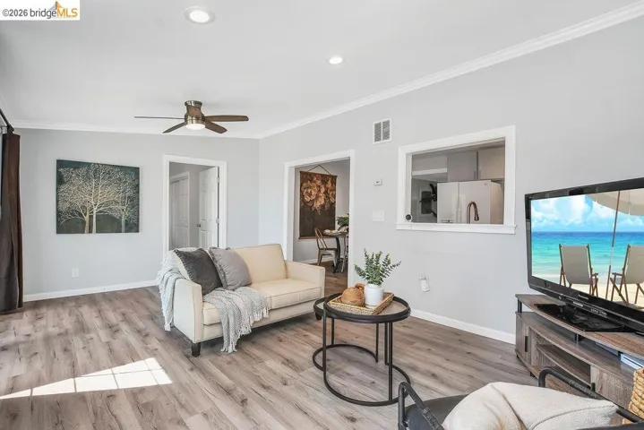 Living room with light wood-style flooring, crown molding, a ceiling fan, and recessed lighting