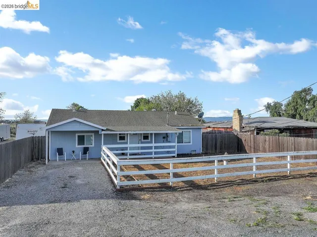 View of front of property featuring a fenced backyard, a patio area, and a shingled roof