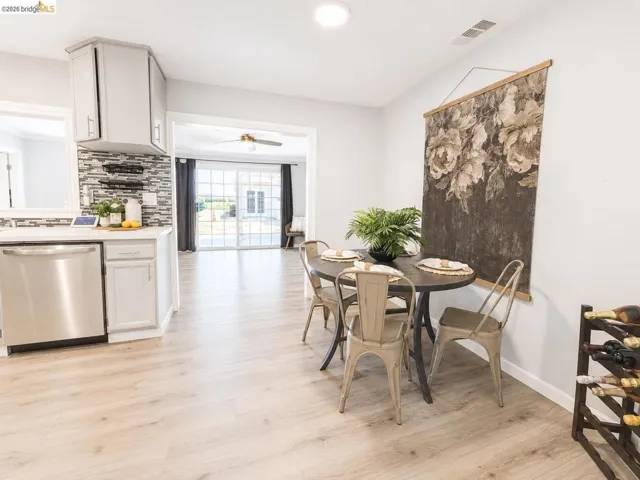 Open-concept living space featuring wood-finish flooring throughout, a modern kitchen with stainless steel appliances, light-toned cabinetry, and a mosaic tile backsplash, and a dining area with recessed lighting