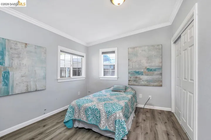 Bedroom with crown molding, wood finished floors, and a closet