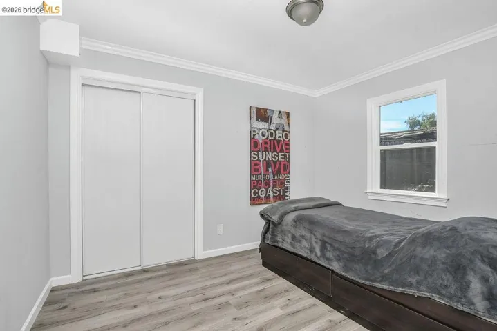 Bedroom with light wood-type flooring, ornamental molding, and a closet