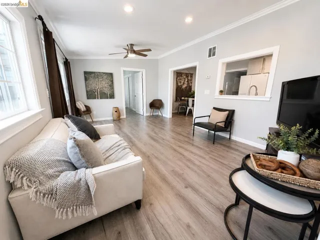 Spacious living area featuring wood-finish flooring, crown molding, recessed lighting, and a ceiling fan