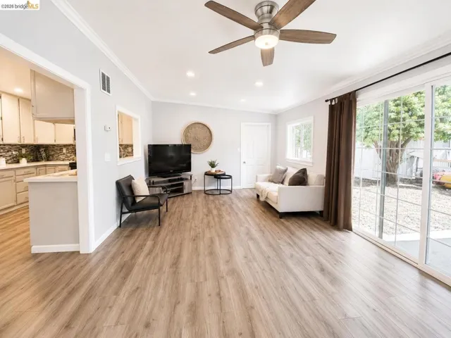 Spacious living area featuring wood-finish flooring, recessed lighting, and crown molding