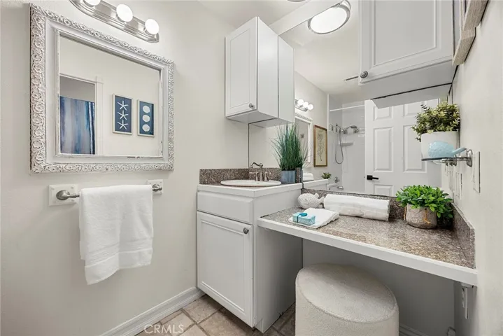 Down the hall offers a full bath with granite countertop, vanity seating area, and ample storage.