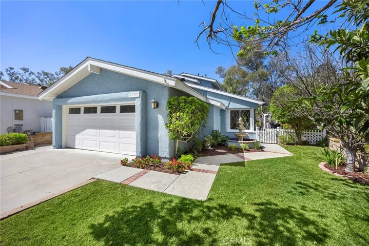 Here’s the home you’ve been waiting for—featuring a manicured lawn, lush landscaping, and a welcoming walkway that leads to the front door, complete with a peaceful fountain and classic white picket fence. The two-car attached garage is equipped with exterior spotlights that illuminate the driveway at night.