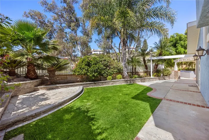 Spacious backyard with plenty of grass area for the kids and dogs to run around and play. Mature palm trees, and a raised paver stone area that was once a koi pond and has since been filled—now offering a unique and versatile space ready for your vision.