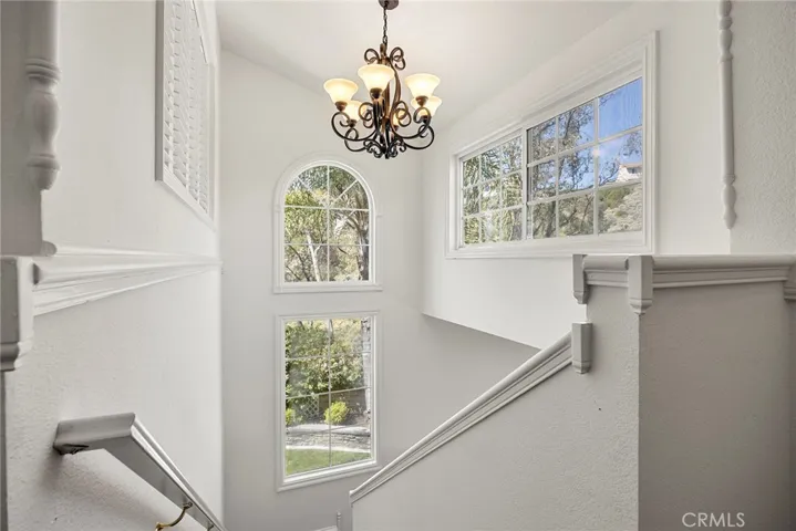 Large windows line the staircase as you head upstairs, filling the space with natural light and offering beautiful outdoor views.