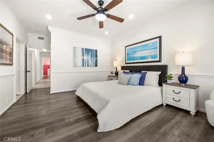 Primary bedroom with easy-care flooring and wainscoting, featuring a modern ceiling fan and recessed lighting already in place.