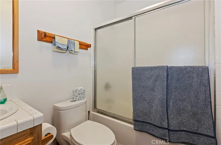 Second bathroom with enclosed tub shower combination.