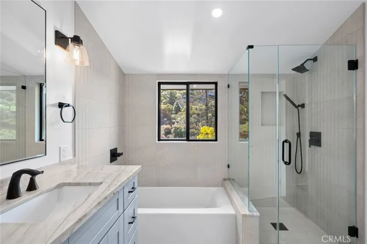  The tranquil primary suite offers a peaceful retreat with a luxurious bath that includes a double vanity, a tub, and a separate shower.