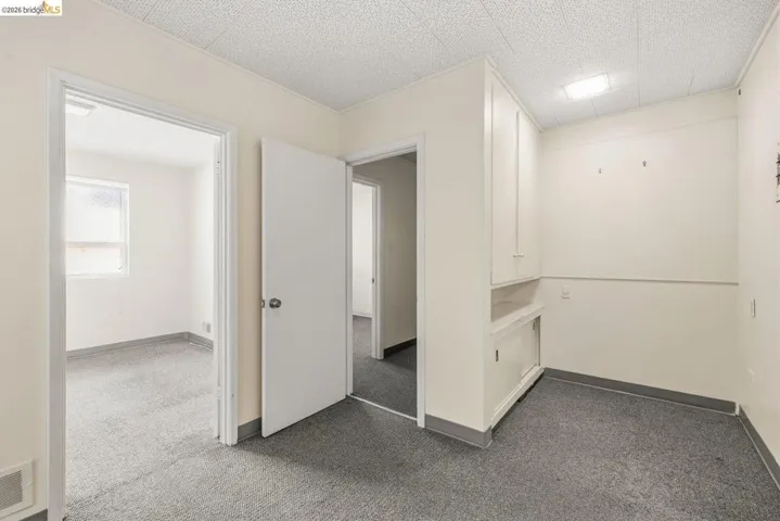 Unfurnished room featuring dark carpet and baseboards