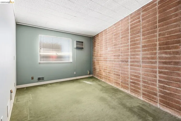 Empty room with carpet, brick wall, and an accent wall