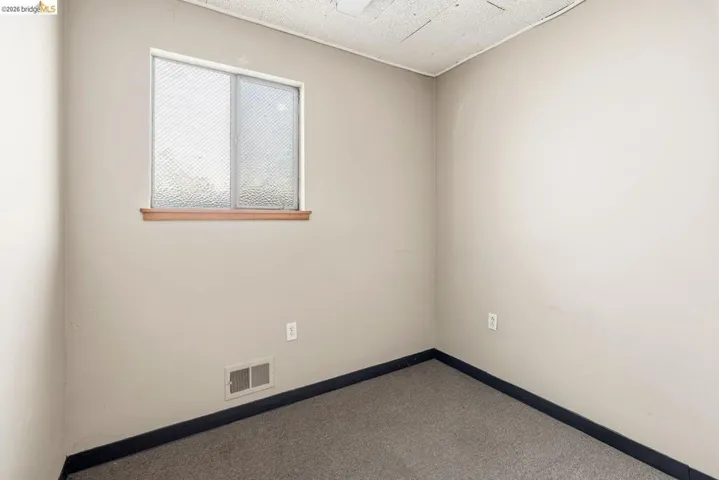 Spare room with dark carpet and baseboards