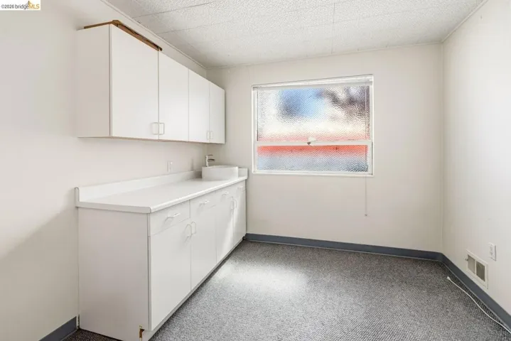 Laundry room with light colored carpet and baseboards