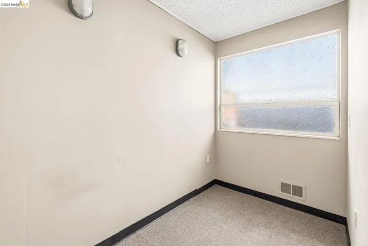 Spare room featuring light colored carpet and a textured ceiling