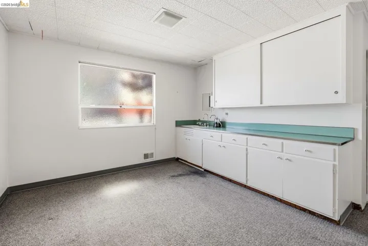 Kitchen featuring white cabinetry, light countertops, and light colored carpet