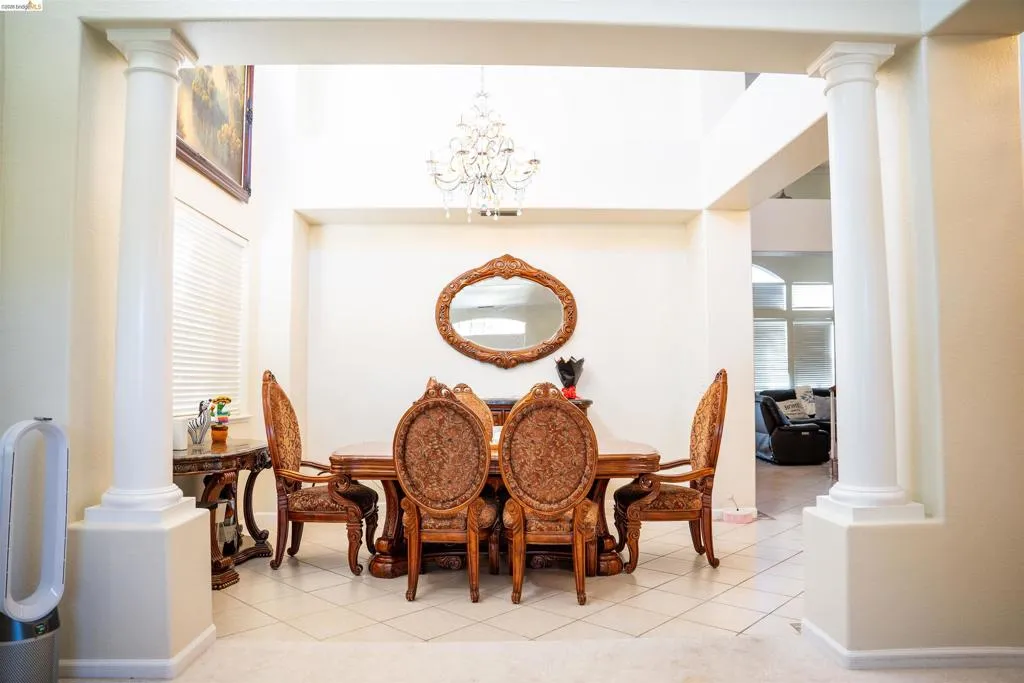 Dining room featuring ornate columns, a chandelier, and light tile patterned floors