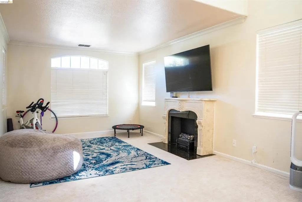 Sitting room featuring light colored carpet, plenty of natural light, crown molding, a high end fireplace, and a textured ceiling