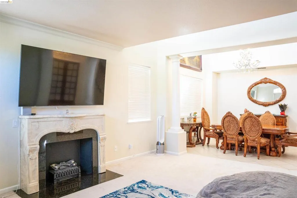 Living area featuring decorative columns, a fireplace, hanging lights, light colored carpet, and light tile patterned floors
