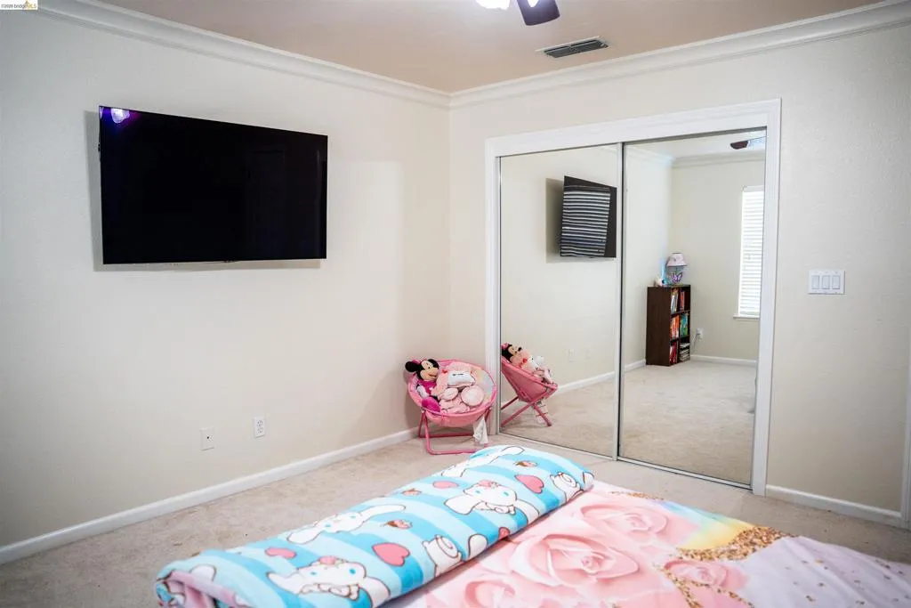 Bedroom featuring ornamental molding, light colored carpet, ceiling fan, and a closet