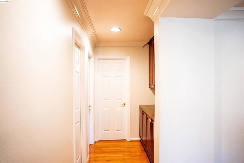 Hallway with ornamental molding, light wood-style flooring, and recessed lighting