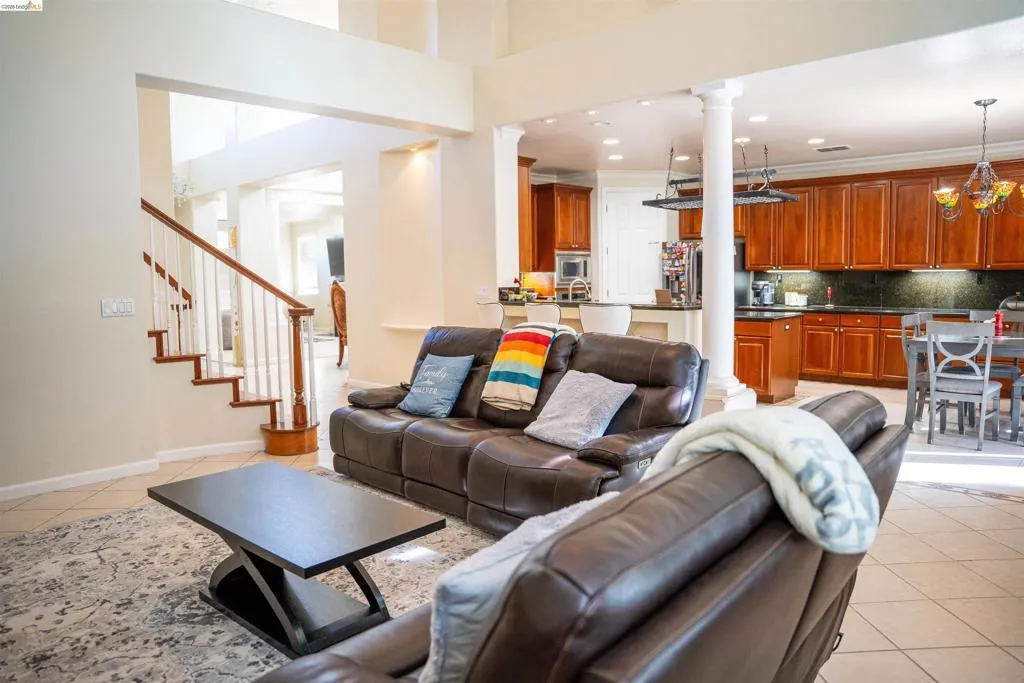 Living area with light tile patterned flooring, decorative columns, and suspended lighting