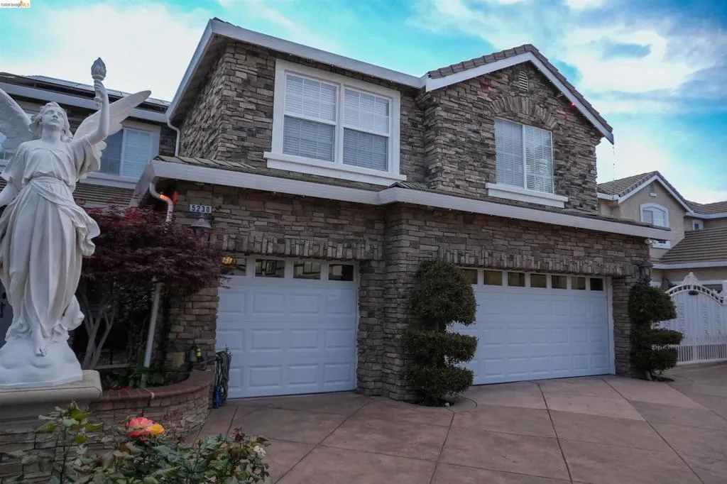 View of side of property with stone siding, an attached garage, and concrete driveway